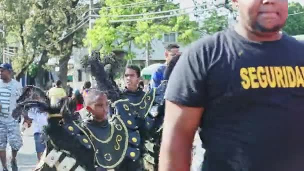 Boys in dark bright costumes walk on dominican city street at carnival annual event — Stock Video