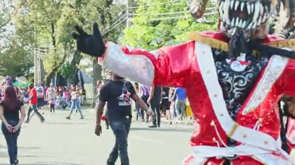 Человек в костюме демона танцует на Доминиканской городской улице на ежегодном мероприятии — стоковое видео