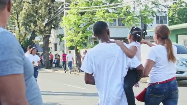 Gente en trajes coloridos marcha en la calle dominicana de la ciudad en el evento anual de carnaval — Vídeos de Stock