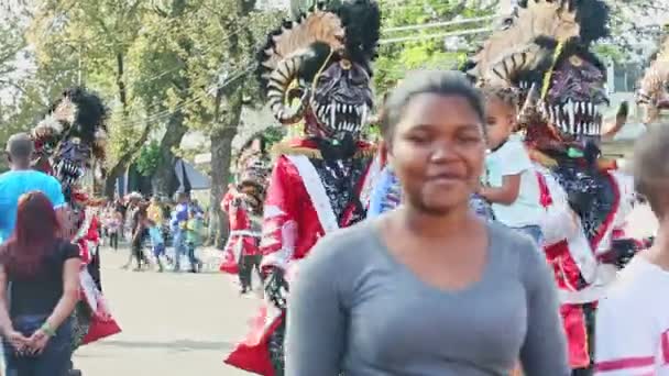 Pessoas com fantasias assustadoras de demônios caminham na rua da cidade dominicana no evento anual do carnaval — Vídeo de Stock