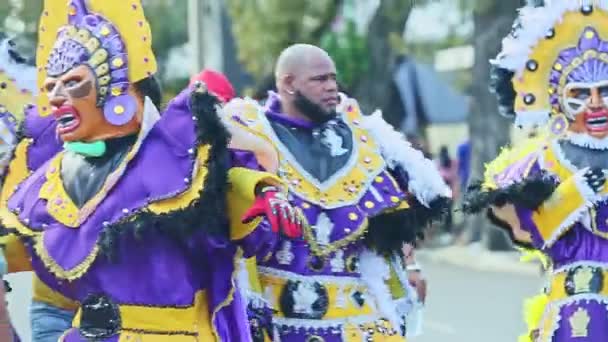 Gente en trajes coloridos caminan en la calle dominicana de la ciudad en el evento anual del carnaval — Vídeos de Stock