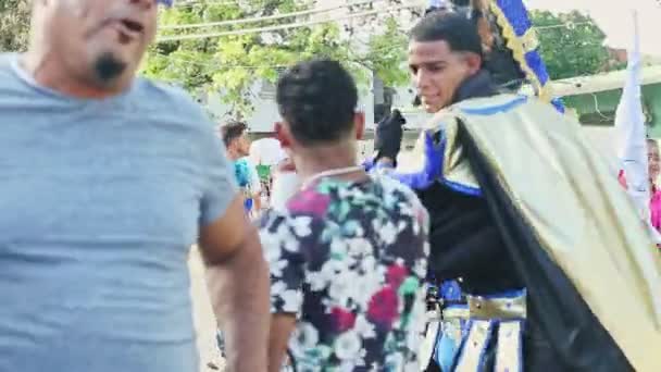 Люди в барвистих костюмах ходять по доміканській міській вулиці на карнавалі щороку. — стокове відео