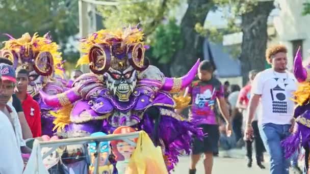 Personas con disfraces de carnaval de demonios caminan por la calle dominicana en el evento anual — Vídeos de Stock