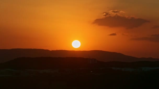 低い山の黒いシルエットの上のオレンジ色の夕日のパノラマ — ストック動画