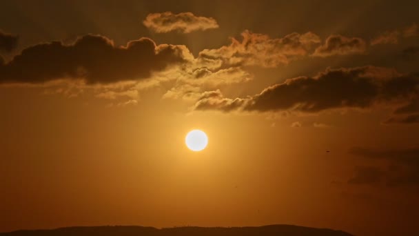 Dark clouds slowly sail on golden sunset sky over black mountains — Stock Video
