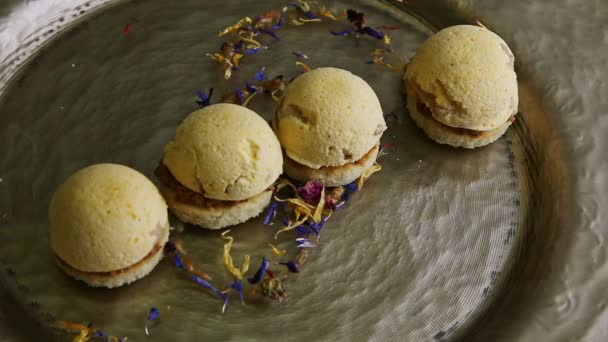 Top view closeup αρχικά διακοσμημένα τέσσερα σφαιρικά μπισκότα σφουγγάρι σε χρυσό πιάτο — Αρχείο Βίντεο