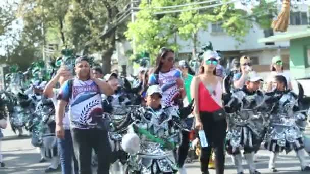 Ludzie w jasnych strasznych kostiumach demonów maszerują na ulicę miasta w Dominican Carnival — Wideo stockowe