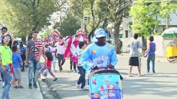 Ludzie w urozmaiconych strojach karnawałowych spacerują ulicą Dominikany na dorocznej paradzie — Wideo stockowe