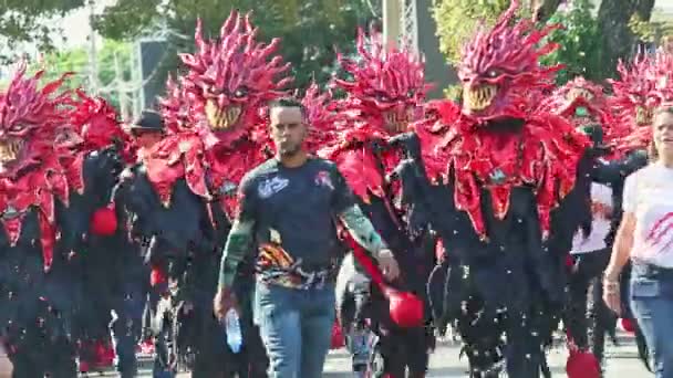 Зум от мужчин в костюмах огненных дьяволов марш на городской улице на Доминиканский карнавал — стоковое видео