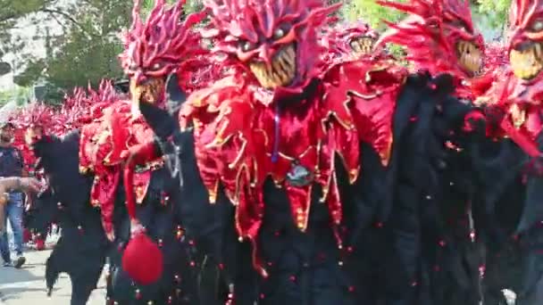 Zoom in at men in scary red demons costumes pose for photo at dominican carnival — ストック動画