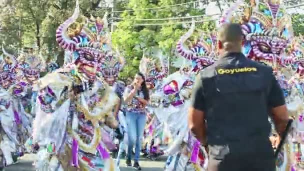 People in variegated masquerade costumes walk on city street at dominican carnival — ストック動画
