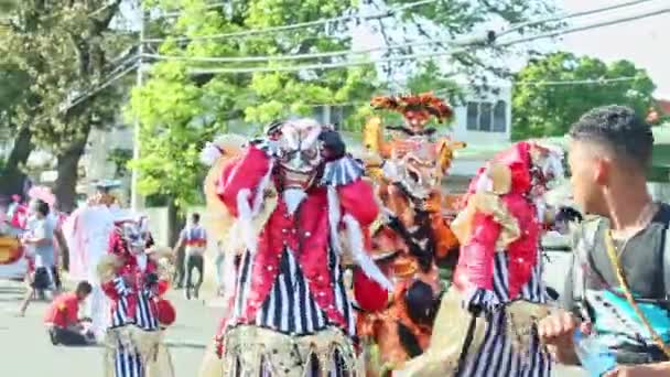 Mensen in gekleurde carnaval kostuums passeren op dominicaanse stad straat op jaarlijkse parade — Stockvideo