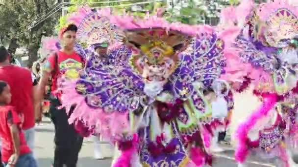 Personas con múltiples disfraces de carnaval caminan por la calle dominicana en el desfile anual — Vídeos de Stock