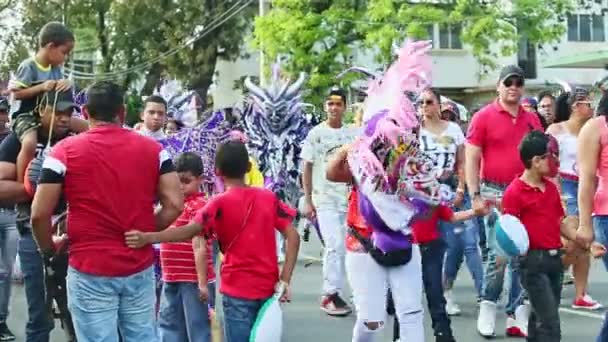 Obywatele w urozmaiconych kostiumach spacerują ulicą miasta na dominikańskim corocznym karnawale — Wideo stockowe