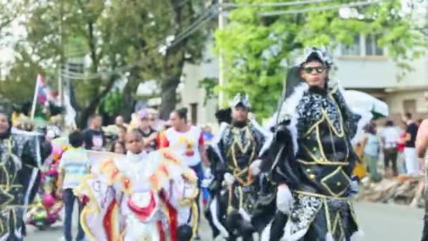 Gente con múltiples disfraces de carnaval demoníaco pasa por la calle de la ciudad en el desfile dominicano — Vídeos de Stock