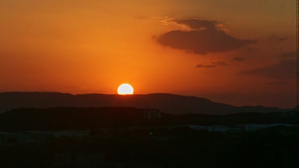 Велике золоте сонце швидко сідає над чорним силуетом низьких гір — стокове відео