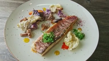 slow zoom in at originally decorated baked fish fillet with vegetables rotates on plate
