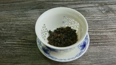 closeup hot water pours in white porcelain teapot with dry tea leaves