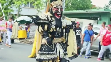 closeup men in scary demon costumes pass on city street at dominican carnival