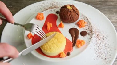 human hands cut yellow cupcake dessert by fork and knife