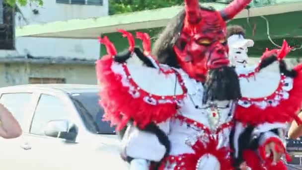 Closeup man in vivid devil carnival costume walk on city street at dominican festival — Stockvideo