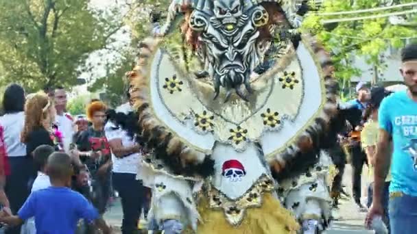 Человек в ярком карнавальном костюме позирует для фотографии на улице на Доминиканском фестивале — стоковое видео