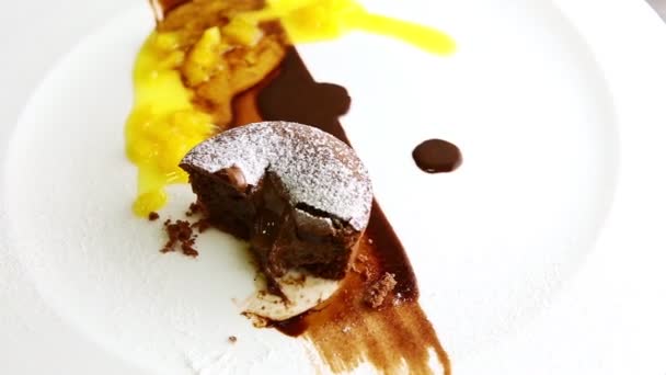 Vista superior primer plano una mitad del postre de pastel de chocolate gira en el plato — Vídeos de Stock