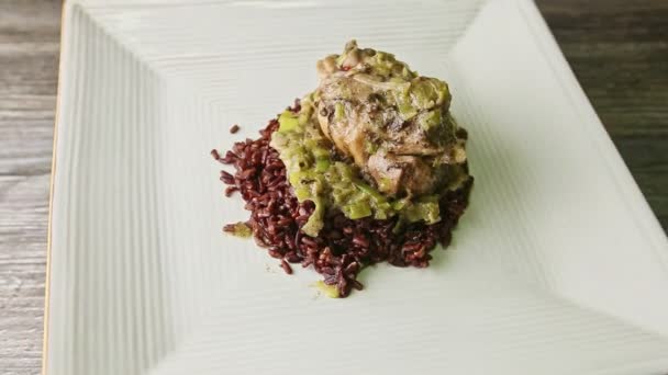 Powolny zoom na smażone przepiórki z zieloną cebulą opatrunek na dzikim ryżu obraca się na talerzu — Wideo stockowe