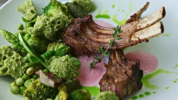 Gros plan finement décoré grandes côtes frites avec légumes verts tourne sur plaque blanche — Video