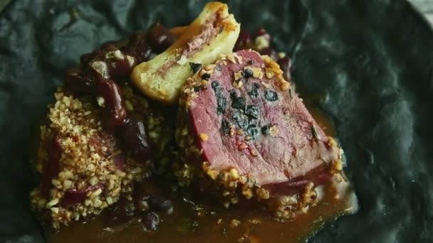 Крупный план модные украшенные гриль мясо стейк вращается на черной тарелке — стоковое видео