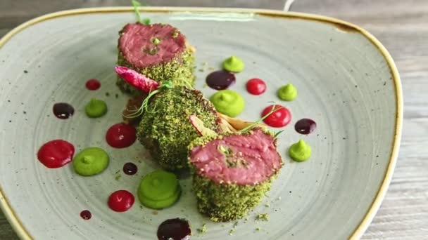 Primer plano piezas de carne horneada decoradas con salsas gira en el plato — Vídeo de stock