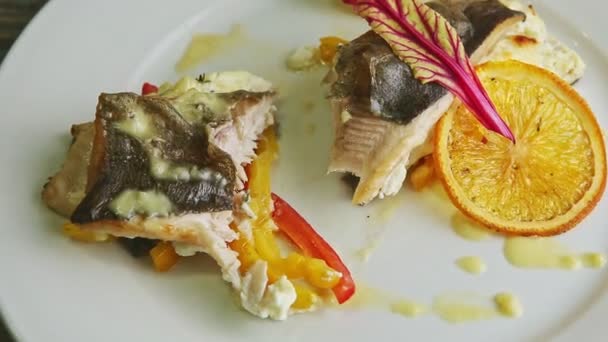 Primo piano a fette metà di pesce di mare al forno farcito con salsa alla panna su piatto bianco — Video Stock