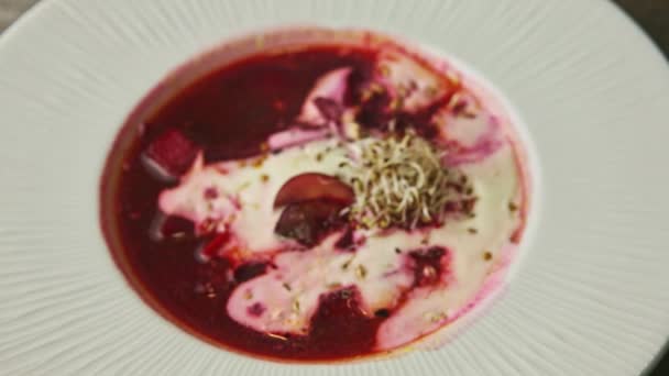 Top view närbild traditionell röd borscht dekorerad med gräddfil och vete groddar — Stockvideo