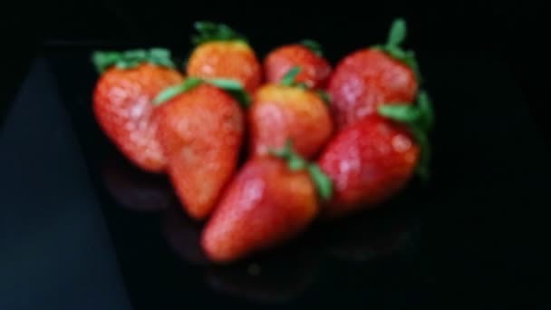 Focus in at group of whole fresh juicy red strawberries lie on black background — 비디오