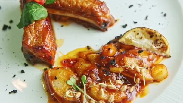 Panorama de primer plano en costillas de carne asadas finamente decoradas en plato blanco — Vídeos de Stock