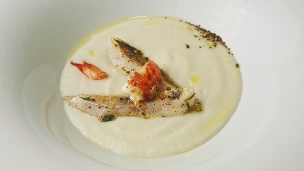 Nahaufnahme: frische weiße Sahnesuppe mit Garnelen und gebratenen Fischstücken — Stockvideo