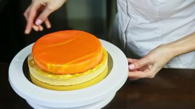 Şekerci beyaz standa turuncu jöleli cheesecake koyar.
