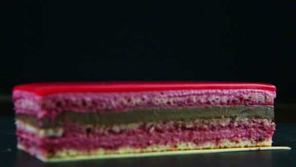 Focus in at piece of chocolate and berry layered cake decorated with pink icing — Stock Video