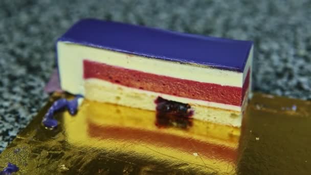 Morceau de gâteau éponge dessert avec mousse blanche et baies garnie de gelée violette — Video