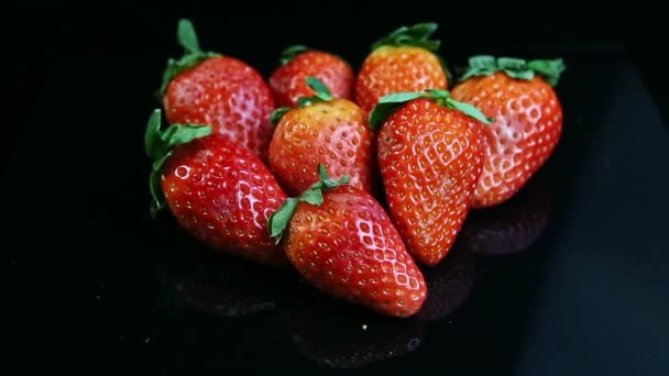 Vrchol pohled na skupinu celé čerstvé šťavnaté červené jahody leží na černém pozadí — Stock video