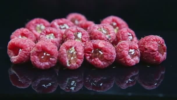 Grupo close-up de framboesas frescas com geléia mentira sobre fundo preto — Vídeo de Stock