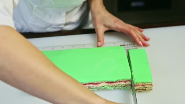 Кондитер, вырезанный ножом сливочный фруктовый слоистый торт с зеленым зеркалом глазури на порциях — стоковое видео