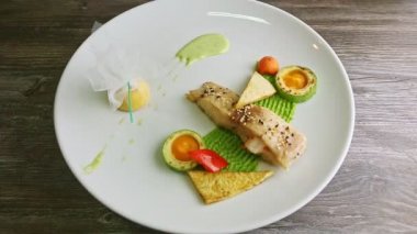 white plate with finely decorated fried fish and garnish spin around