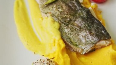 closeup panorama on fried fish fillet on potato purre and vegetables rotates on plate