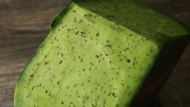 Bovenaanzicht op groot stuk groene kaas met kruiden ronddraaiend op klein bord — Stockvideo