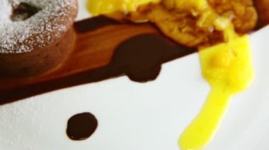 closeup sugar powdered chocolate cake with syrups rotates on plate