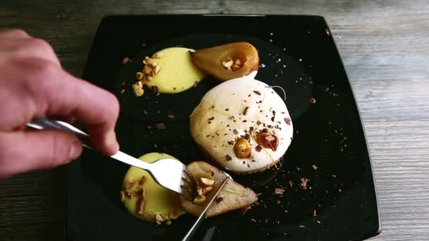 Hand slice caramelized pear half with fork and knife — Stock Video