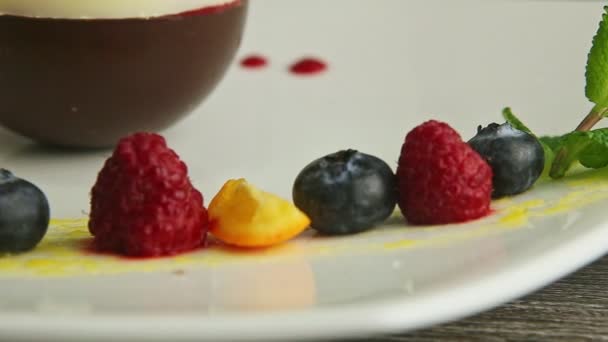 Closeup row of blueberry, raspberry, orange, and mint on white plate — Stockvideo