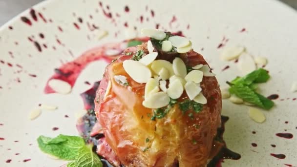 Slow zoom out from baked apple with syrup and nuts rotates on plate — Stok video