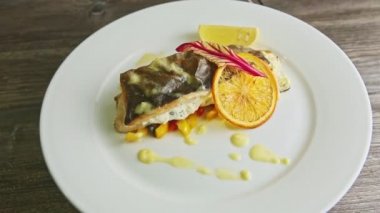 top view on exquisite decorated stuffed sea fish on sliced peppers rotates on plate